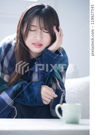 一位穿著冬季睡衣的女人的特寫，她感冒得厲害，頭痛嚴重 119927545