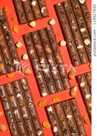 Lots of chocolate bars with nuts and raisins on a red background 119927840