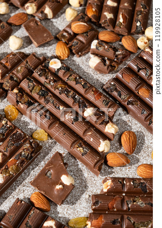 Broken chocolate pieces with nuts and raisins on a stone background top view 119928105