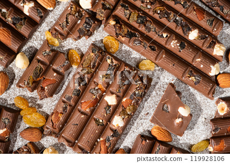 Broken chocolate pieces with nuts and raisins on a stone background top view 119928106
