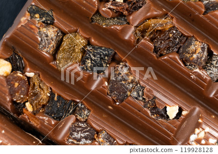 Macro background of milk nut chocolate with raisins. 119928128
