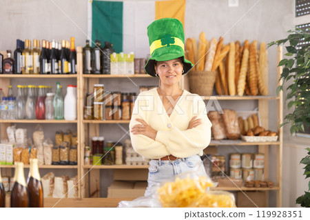 Positive female store clerk in green hat is preparing to meet customers on eve of St. Patricks Day Positive female store clerk in green hat is preparing to meet customers on eve of St. Patricks Day 119928351
