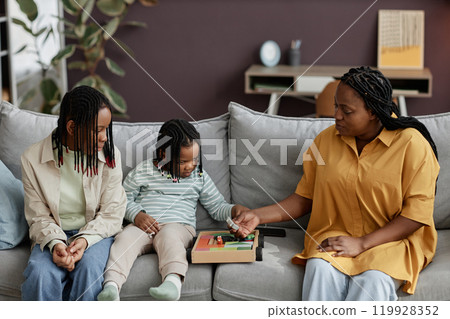 Family enjoying interactive play session on sofa with various toys and activities around Living room decorated with contemporary furniture and plants creating cozy atmosphere Family enjoying interactive play session on sofa with various toys and activities around Living room decorated with contemporary furniture and plants creating cozy atmosphere 119928352