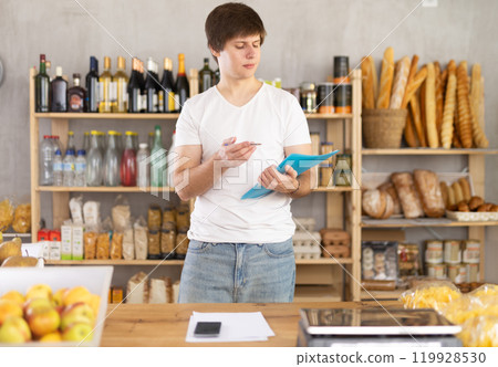 Man seller manager in shop make calculations, work with paper documents and count using phone 119928530