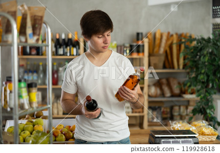 Young man choosing whiskey in supermarket Young man choosing whiskey in supermarket 119928618