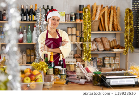 Positive store clerk in Santa hat is preparing to meet customers on Ney Year Eve. Positive store clerk in Santa hat is preparing to meet customers on Ney Year Eve. 119928630