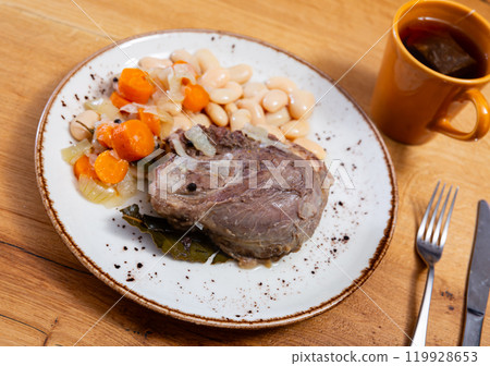 Pork cheeks served with beans on plate 119928653