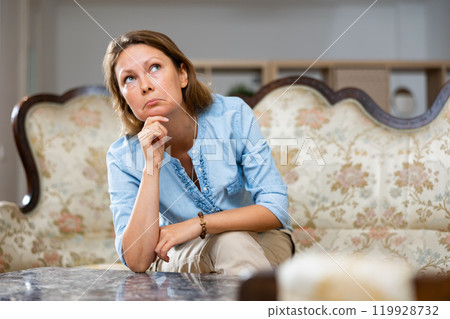 Sad woman sitting on sofa at home 119928732