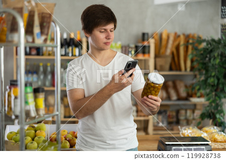 Male buyer scan pickled olives label in store 119928738