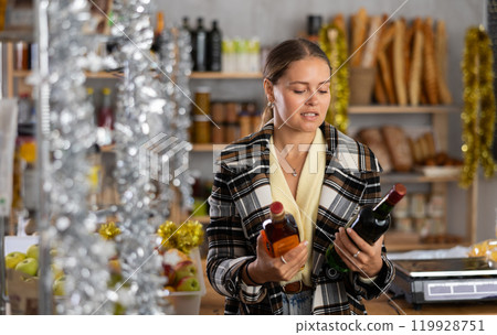On New Years Eve, girl shopper compare wine and whisky, buys alcoholic beverages On New Years Eve, girl shopper compare wine and whisky, buys alcoholic beverages 119928751