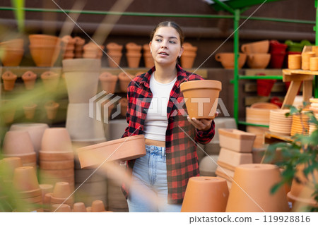 Young girl amateur gardener looking for flowerpots at garden market 119928816