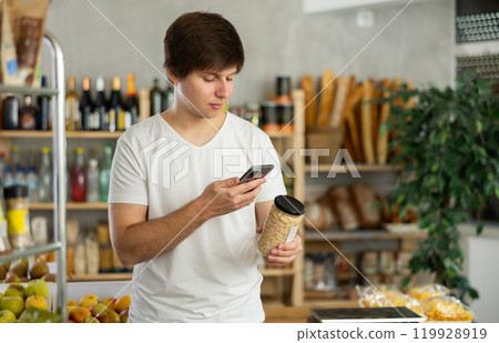 Guy purchaser scanning QR code or barcode of canned beans in supermarket Guy purchaser scanning QR code or barcode of canned beans in supermarket 119928919
