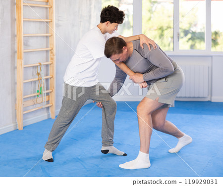 Teenage boy and middle-aged man training throwing method during self-defense courses Teenage boy and middle-aged man training throwing method during self-defense courses 119929031