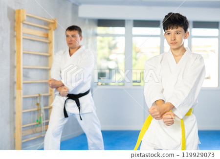 Teen boy wearing kimono training karate techniques during workout session 119929073