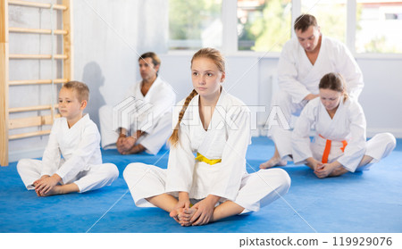 Big family before training karate martial arts performs stretching butterfly 119929076