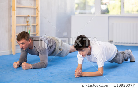 Man and teenage boy train their abs 119929077