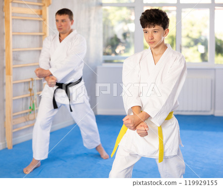 Teen boy wearing kimono training karate techniques during workout session 119929155