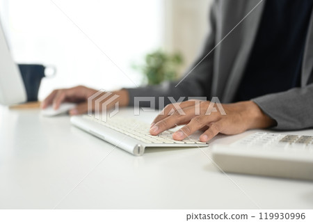Close up of businessman typing on wireless keyboard at modern workspace Close up of businessman typing on wireless keyboard at modern workspace 119930996