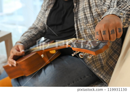 Close up of young man playing acoustic guitar. Leisure activity and hobby concept Close up of young man playing acoustic guitar. Leisure activity and hobby concept 119931130