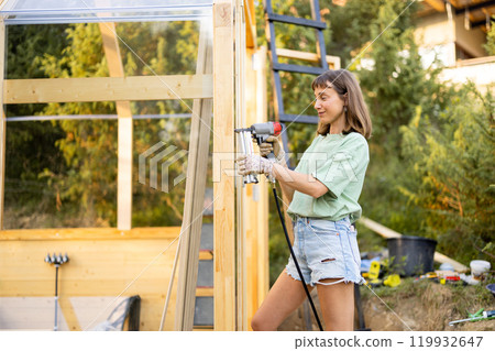 Female Carpenter Using Nail Gun Female Carpenter Using Nail Gun 119932647