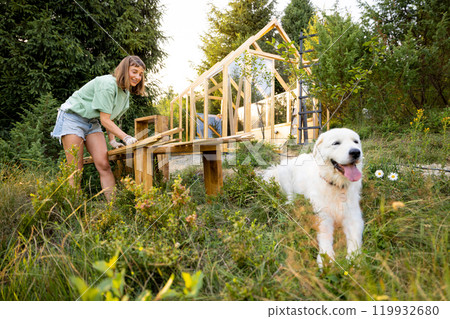 Woman building greenhouse at backyard Woman building greenhouse at backyard 119932680