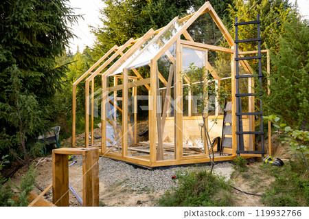 A wooden greenhouse under construction A wooden greenhouse under construction 119932766