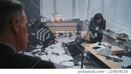 Female forensic scientist takes photos of evidence, police officer searches fingerprints 119934526