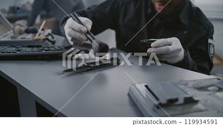 Murder case: Close up of African American police criminalist searching fingerprints on knife Murder case: Close up of African American police criminalist searching fingerprints on knife 119934591