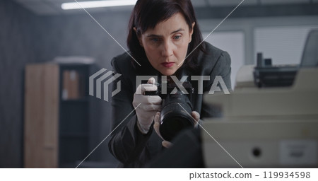 Female criminalist takes photos of evidence at crime scene with camera Female criminalist takes photos of evidence at crime scene with camera 119934598
