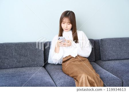 便衣的年輕女人，客廳，智能手機 119934613
