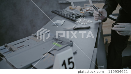 Crime scene evidence. Rack focus on forensic scientist looking for fingerprints Crime scene evidence. Rack focus on forensic scientist looking for fingerprints 119934621