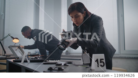 Female criminalist takes photos of clues, policeman searches fingerprints 119934626