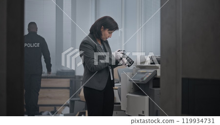 Investigation team working at crime scene. Female criminalist takes photos of evidence Investigation team working at crime scene. Female criminalist takes photos of evidence 119934731