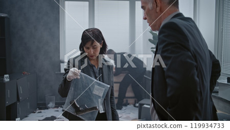 Female criminalist packs murder weapon in zip lock bag, talks to colleague Female criminalist packs murder weapon in zip lock bag, talks to colleague 119934733