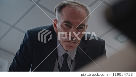 Low angle of serious detective looking suspiciously, working at crime scene Low angle of serious detective looking suspiciously, working at crime scene 119934738