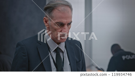 Investigation team working: Male detective in suit examines evidence at crime scene 119934746