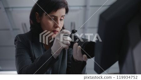 Close up of female criminalist taking photos of evidence at crime scene with camera 119934752