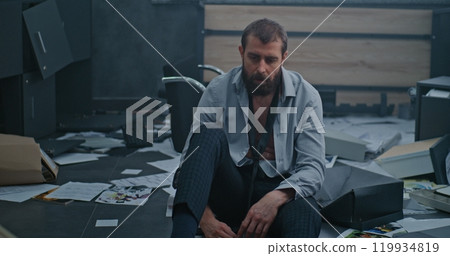 Nervous businessman sits down on floor after destroying office due to failed business deal Nervous businessman sits down on floor after destroying office due to failed business deal 119934819