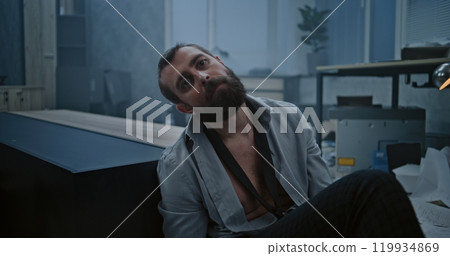 Depressed businessman sits on the floor in destroyed office room Depressed businessman sits on the floor in destroyed office room 119934869
