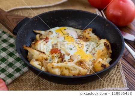 fried omelette with cauliflower and vegetables in a frying pan on a wooden table fried omelette with cauliflower and vegetables in a frying pan on a wooden table 119935458