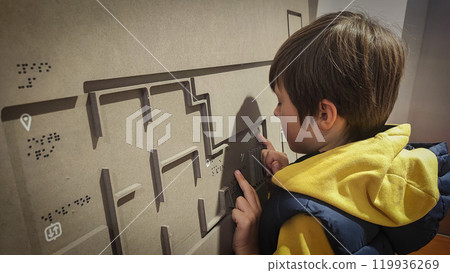 A boy reading the evacuation plan on the wall in braille. Close-up of a child reading braille. The concept of inclusiveness. World Sight Day. World Braille Day 119936269