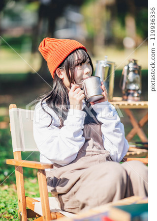戴著針織帽的年輕女子在營地喝酒放鬆 119936336