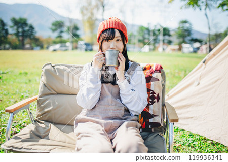 戴著針織帽的年輕女子在營地喝酒放鬆 119936341