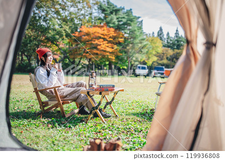 Young woman relaxing with a drink in camp Young woman relaxing with a drink in camp 119936808