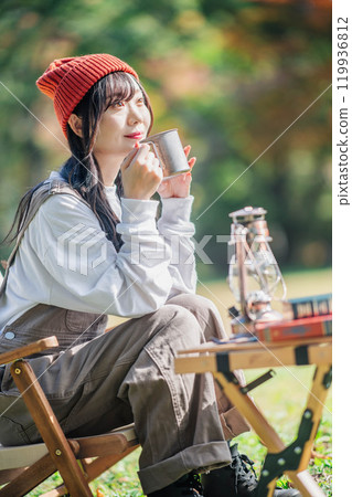 Young woman relaxing with a drink in camp Young woman relaxing with a drink in camp 119936812
