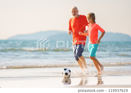 Grandfather and kids play football on beach. Grandfather and kids play football on beach. 119937629