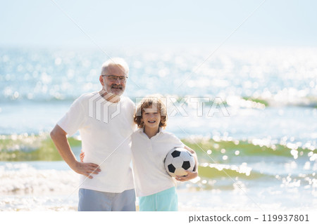 Grandfather and kids play football on beach. 119937801