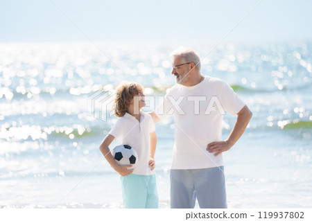 Grandfather and kids play football on beach. 119937802