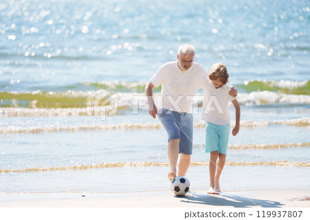 Grandfather and kids play football on beach. 119937807