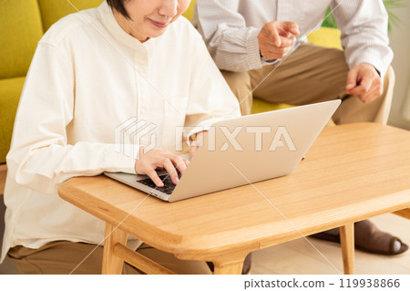 A middle-aged to senior couple looking at a computer in the living room A middle-aged to senior couple looking at a computer in the living room 119938866